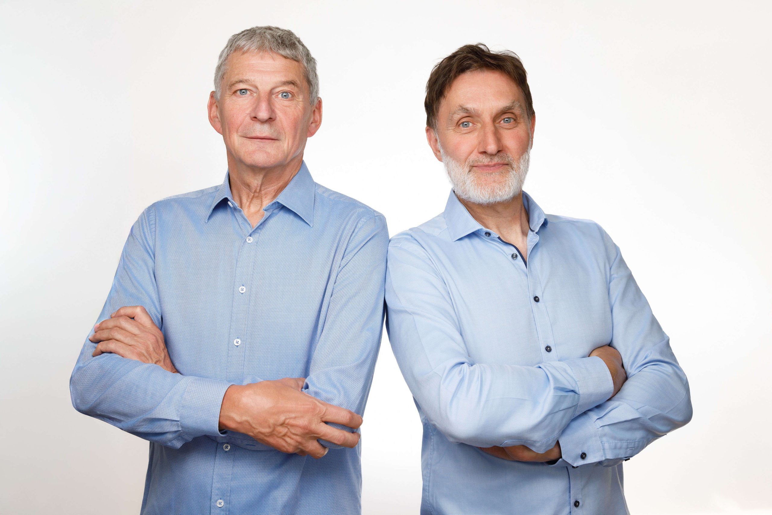 zwei Männer in hellblauen Hemden stehen nebeneinander